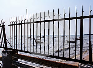 Fishing boat mooring in sea with rusty fench foreground