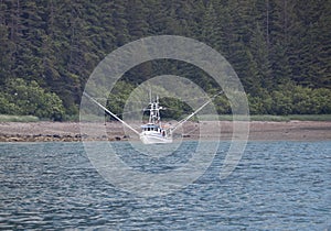 Fishing boat near shore with stabilizers extended.