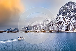 Fishing boat in Norway Lofoten aerial landscape in winter time with rainbow and mountains covered in snow