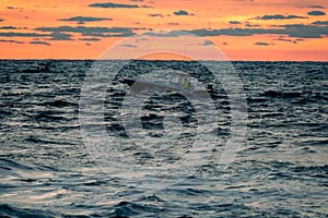 A fishing boat out on the ocean at sunrise