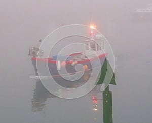 Fishing boat passing the starboard channel marker in the dawn fog in Mevagissey harbour south Cornwall England