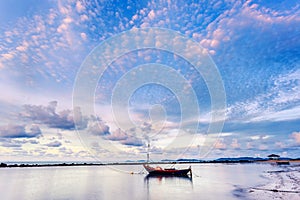 Fishing boat in perfectly calm sea water like glass with the clouds in the sky, long Exposure taken during sunrise