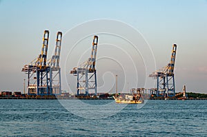 Fishing boat puts out to sea from Cochi port, with heavy industry in the background