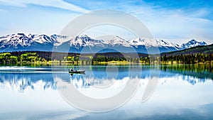 Fishing Boat on Pyramid Lake in Jasper national Park, Alberta, Canada with the snow capped peaks of the Rocky Mountains