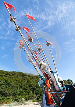 Fishing boat with red and white flags on a blue sky background.