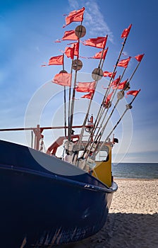 Fishing boat with red and white flags on a blue sky background