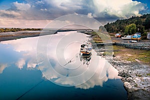 Fishing boat in the reflection of the cloud on the river by the ocean, Aytuy, Chiloe island, Chile, South America