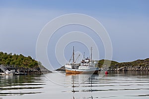 A fishing boat reflects in the calm waters of a quiet Lofoten inlet