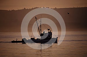 Fishing boat returning from the sea at sunrise min Monterey Bay.