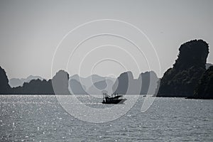 Fishing boat sailing across in Ha Long Bay