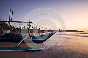 Fishing boat on sand beach at colorful dawn