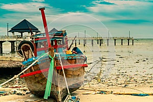 Fishing boat on sand beach near the bridge and sea. Relaxation on paradise tropical beach and resort concept. Garbage on beach