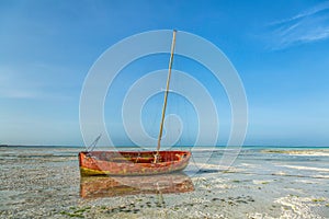 A fishing boat on sand during low tide in Zanzibar