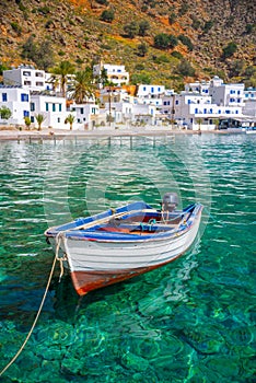 Fishing boat and the scenic village of Loutro in Crete Greece