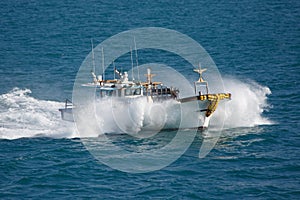 Fishing boat in sea splashes, floats with high speed