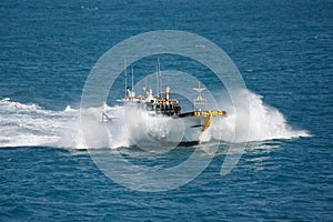 Fishing boat in sea splashes, floats with high speed