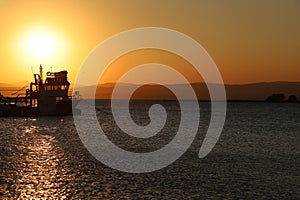 Fishing boat silhouette with yellow and orange sunset colors in the background