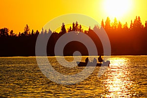 A fishing boat silhouetted against a brilliant orange sky