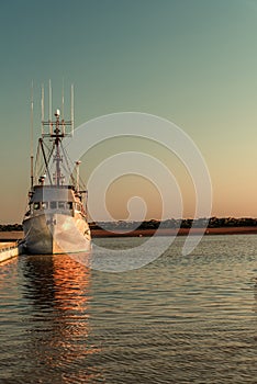 fishing boat stands at the dock in the rays of the evening sunset