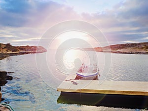 Fishing boat at sunset calm water. A motorboat for sport fishing tied to a wooden pier