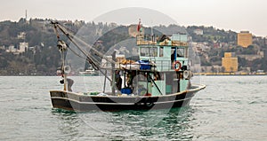 Fishing boat surfing on the sea front of historical Rumeli rampart cityscape photo