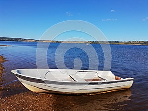 Fishing boat on a wonderful blue lake on the mountain. Beautiful landscape, in the background hills, forest and sky