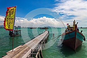 Fishing boat by a wooden bridge and a chinese flag in Tan Jetty, part of the Clan Jetties, Georgetown, Penang, Malaysia