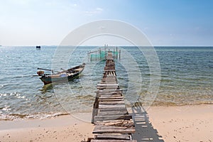 A fishing boat and wooden walkway to the cages with fish