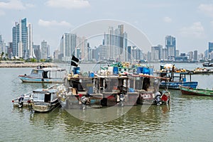 Fishing boats at commercial fish market harbour with skyline bac