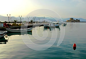 Fishing boats floating in the pretty harbor in Nafplio in Greece with Bourtzi Castle in the background