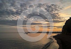 Fishing boats are floating on the shores of Lovina beach at sunrise.