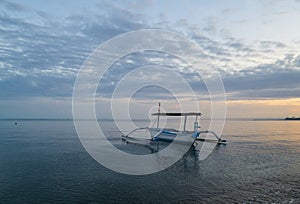 Fishing boats are floating on the shores of Lovina beach at sunrise.