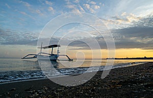 Fishing boats are floating on the shores of Lovina beach at sunrise.