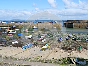 Fishing boats lie at low tide on the sandy bottom in front of the pier of the harbor in Mousehole in Cornwall England