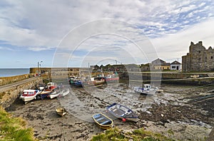 Fishing Boats lie on the silt at low tide in the inner harbour of Slade Village, overlooked by the Castle and ruins.