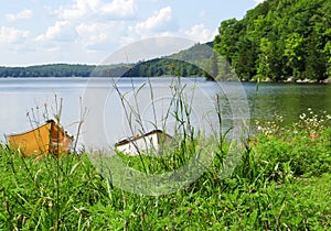 Fishing boats moored in the grass shore of Philippe Lake surrounded by green mountains Quebec