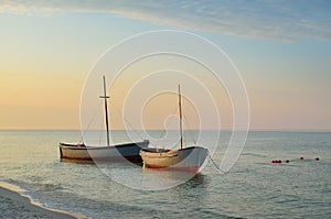 Fishing boats moored near the shore at sunset background