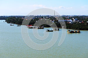 Fishing boats at the mouth of the Thu Bon River with the city of Hoi An, Vietnam in the background