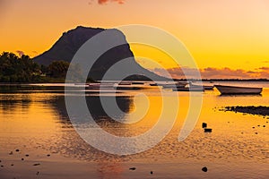 Fishing boats in ocean at sunset time. Le Morn mountain in Mauritius