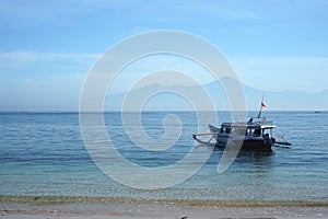 Fishing boats on the pink beach of Lombok with Mount Rinjani in the background.