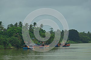 Fishing boats in the river estuary of Sungai Kelantan River during cloudy day before storm in Kelantan, Malaysia.