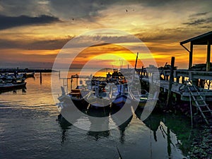 Fishing boats in sea against sky during sunset