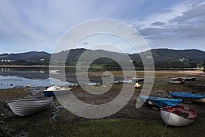 Fishing boats on the shore of a lake surrounded by forested mountains in Gernika, Biscay, Spain