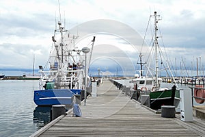 Fishing boats at the wooden dock in the port of Sassnitz on the island of Rugen in the Baltic Sea against a cloudy sky, travel and
