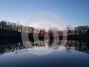 Fishing bobber hits still water causing ripples for evening dawn bite at sunrise sunset on winter day