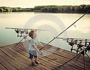 Fishing equipment. Boy fisherman with fishing rods on wooden pier