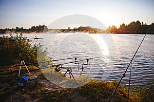 Fishing equipment on seat on lake. Feeder carp rods on sunrise
