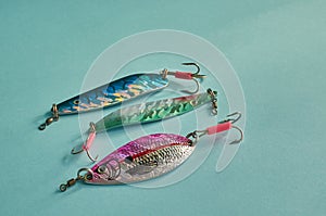 Fishing equipment. Three metal fishing lures on a blue background