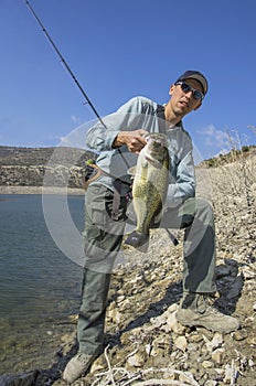 Fishing. Fisherman with bass fish in hand