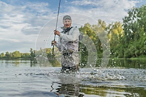 Fishing. Fisherman catch fish in water at river on blurred background with splashing and drops